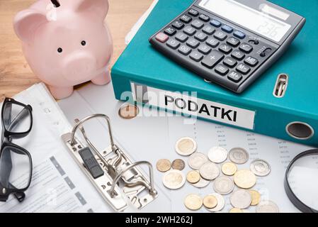 Polnisches Steuerkonzept mit Münzen und Taschenrechner. Binder mit Podatki bedeutet Steuern Stockfoto
