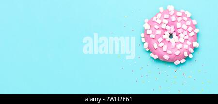 Rosa Donut mit Murshmallow und Streuseln, Blick von oben auf blauem Hintergrund Stockfoto