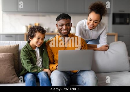 Eine glückliche Familie, die die Zeit mit einem Notebook zu Hause genießen kann Stockfoto