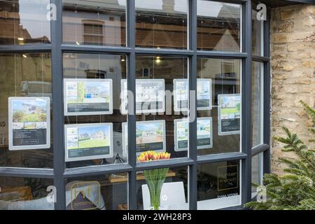 Fenster des Immobilienmaklers mit Bildern von Häusern zum Verkauf, Tetbury, Gloucestershire, Großbritannien Stockfoto