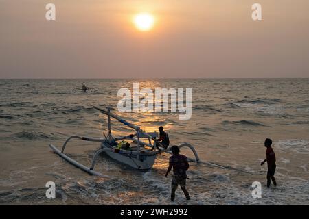 01.11.2023, Senggigi, Lombok, IDN - Maenner haben ein Jukung bei Sonnenuntergang ins Meer geschoben. Ein Jukung ist ein traditionelles indonesisches Fischerboot. Abend, Abendlicht, Abends, Alltag, asiatisch, Asien, Auslegerboot, Aussen, Aussenaufnahme, Boot, Daemmerung, Fischer, Fischerboot, Fischerboote, Fischerei, Gegenlicht, Gegenlichtaufnahme, Gesellschaft, Gewaesser, Herbst, Himmel, Horizont, Indonesien, indonesisch, Jahreszeit, Jukung, Kueste, Lombok, Meer, Menschen, Personen, QF, Querformat, Rueckansicht, Senggigi, Senggigi Beach, Sonnenuntergang, Strand, Suedostasien, traditionell, Ufe Stockfoto