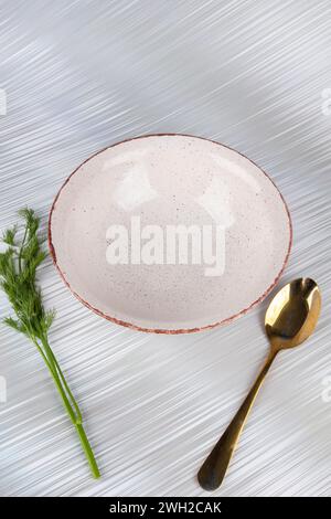 Weiße leere, tiefe Tonplatte mit einem Löffel auf weißem Hintergrund. Stockfoto