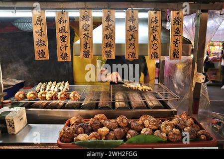 TAIPEI, TAIWAN - 4. DEZEMBER 2018: Händler verkauft große Grillschnecken auf dem Raohe Night Market in Taipei. Nachtmärkte sind ein wichtiger Teil der taiwanesischen Kultur Stockfoto