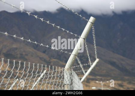 Hoher Zaun mit Stacheldraht um den Flughafenrand in Neuseeland. Stockfoto