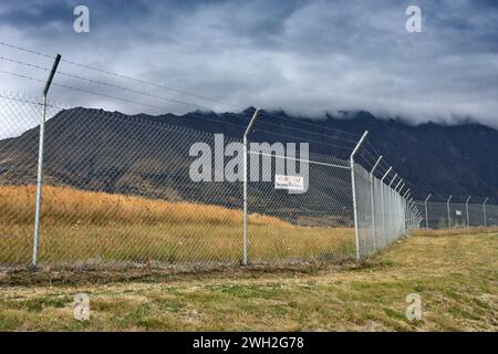 Hoher Zaun mit Stacheldraht um den Flughafenrand in Neuseeland. Stockfoto