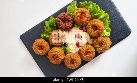 Ein Blick von oben auf frische vegetarische Falafels mit Hummus Dip und Salat serviert auf einer schwarzen Steinuntersetzer. Stockfoto