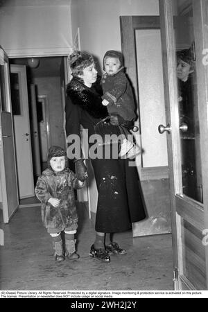 In den 1930er Jahren Eine Mutter in ihrem Kindergarten mit einem Kind am Arm und einem mit der Hand. Dezember 1939. Kristoffersson Ref. 30-4 Stockfoto