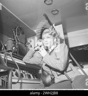 Damenmode in den 1940er Jahren Eine junge Frau in einer karierten Jacke und einem passenden Hut. Auf dem Bild, wie Sie etwas auf den Ohrhörern hören. Sie ist Schauspielerin Dioris Söderström. Schweden 1945. Kristoffersson Ref. P73-5 Stockfoto