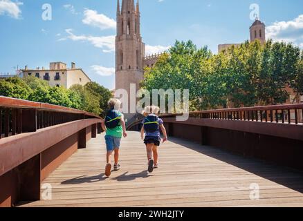 Kindertouristen mit Rucksäcken laufen auf der Brücke in Girona Stockfoto