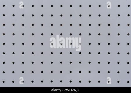 Textur von Aluminiumblechen mit regelmäßig gestanzten kreisförmigen Löchern als Hintergrund. Stockfoto