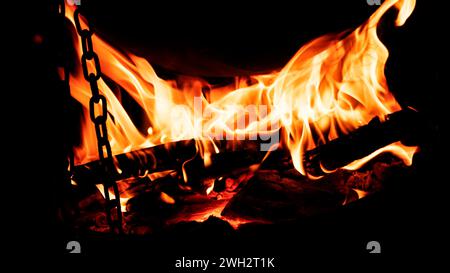 Kochen auf einem Kessel am Feuer. Flammen aus Feuer im Dunkeln. Stockfoto