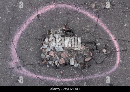 Tiefe Grube auf der Straße. Schlechter Zustand des Asphaltbelags auf der Straße. Straßenreparatur. Stockfoto