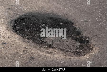 Tiefe Grube auf der Straße. Schlechter Zustand des Asphaltbelags auf der Straße. Stockfoto