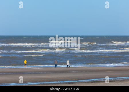 Egmond aan Zee, Niederlande - 17. März 2022: Breiter Sandstrand in der Sonne mit nur einigen Leuten auf einem Spaziergang Stockfoto