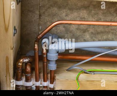 Verschiedene Kupfer- und Kunststoffrohre mit Anschlüssen für heißes kaltes Wasser und Heizung in einem britischen Wohnhaus Stockfoto