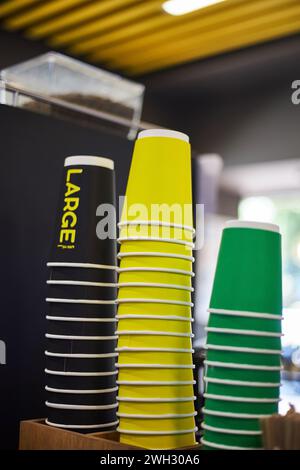 Farbige Pappbecher, schwarz groß, gelb mittelgroß, grün kleine Tasse verschiedene Größen für heiße Getränke, Kaffee, Tee zum Mitnehmen. Mockup für Coffee Shop, Laden Stockfoto