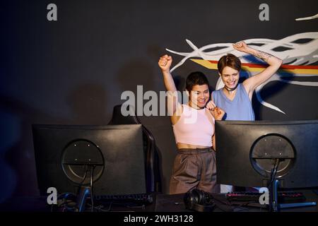 Glückliche Freundinnen, die auf den Computermonitor schauen und den Sieg feiern, Gewinner des Cybersports Stockfoto