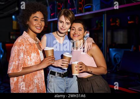 Eine Gruppe glücklicher Frauen, die einen Abend verbringen, mit warmem Lächeln und Kaffeetassen in den Händen Stockfoto
