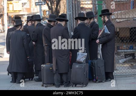 An einem kalten Wintertag wartet eine Gruppe orthodoxer Satmarer Juden auf einen Bus, der sie zu einem Talmud-Kurs in einem anderen Teil von Brooklyn, New York, bringt. Stockfoto