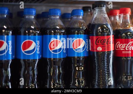 Konkurrierende Limonadenflaschen aus Kunststoff in einem Regal im Supermarkt. Pepsi und Coca Cola Brand Zero, klassisch. Getränk, beliebte kohlensäurehaltige Erfrischungsgetränke Stockfoto