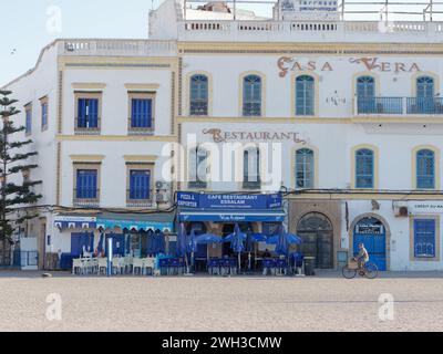 Hauptplatz, während ein Radfahrer in der Nähe eines Restaurants in Essaouira, Marokko, vorbeifährt. Februar 2024 Stockfoto