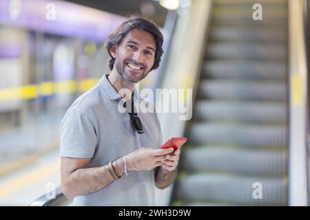 Blick auf einen jungen Mann mit einem Smartphone in einer U-Bahn-Station mit einer verschwommenen Landschaft im Hintergrund. Hochwertige Fotos. Textnachrichten auf t Stockfoto