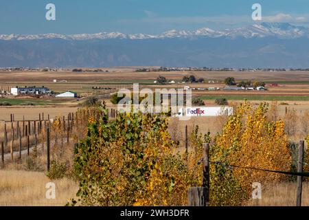 Keenesburg, Colorado – Ein FedEx-Lkw auf einer Landstraße in den östlichen Ebenen Colorados, mit den Rocky Mountains in der Ferne. Stockfoto