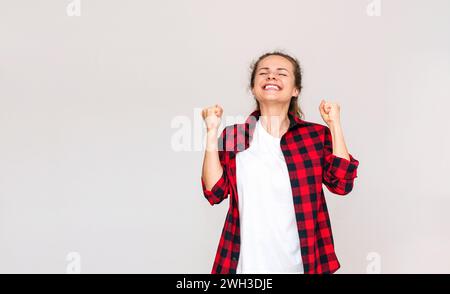 Glückliche junge brünette Frau in lässigen Kleidern, die Gefühle von Freude, Sieg und Glück zeigt. Stockfoto