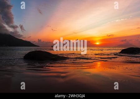 Beau Vallon Beach bei Sonnenuntergang. Küstenlandschaft mit Silhouetten von Küstenfelsen. Mahe Island, Seychellen Stockfoto