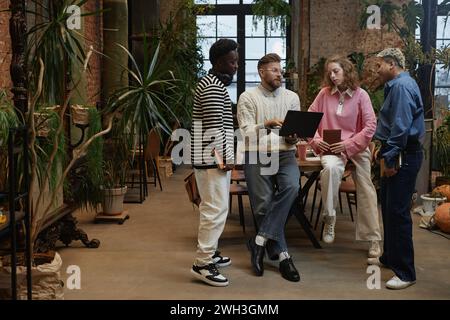 Porträt in voller Länge von verschiedenen jungen Geschäftsteams, die ein Projekt diskutieren, das im Coworking Space im Kopierraum steht Stockfoto