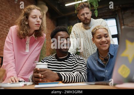 Niedriger Blickwinkel bei verschiedenen jungen Geschäftsteams, die während der Besprechung im Coworking Space auf den Computerbildschirm schauen Stockfoto
