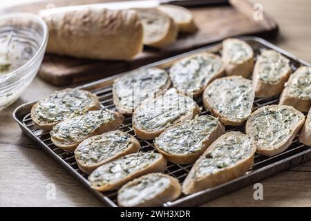 Mini-Baguettes mit Kräuter-Knoblauchbutter, fertig zum Backen auf einem Tablett. Stockfoto