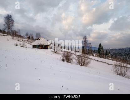 Landschaft Hügel, Haine und Ackerland im Winter abgelegenen alpinen Bergdorf, und kleine alte verlassene Haus am Hang Stockfoto