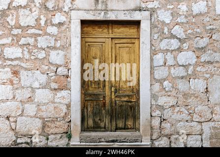 Rustikale gelbe Holztür an einem alten Steinhaus Stockfoto