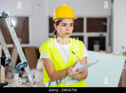 Konzentrierte weibliche Sicherheitsinspektorin macht Notizen auf der Baustelle Stockfoto