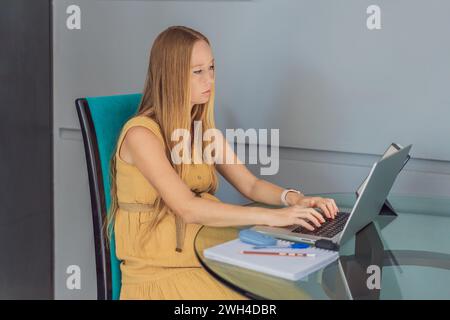 Schöne schwangere Frau, die am Laptop arbeitet. Eine junge Geschäftsfrau, die in ihrem Büro arbeitet Stockfoto