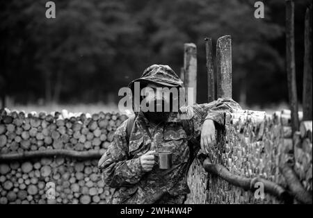 Porträt des Reisenden Mann trinken Tee oder heißen Kaffee mit Emaille-Tasse, Metall-Becher. Reise Lifestyle Landschaft und Abenteuer Konzept. Mensch in der Natur. Stockfoto