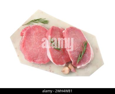 Brett mit Stücken rohem Schweinefleisch, Rosmarin und Knoblauch isoliert auf weiß, Blick von oben Stockfoto