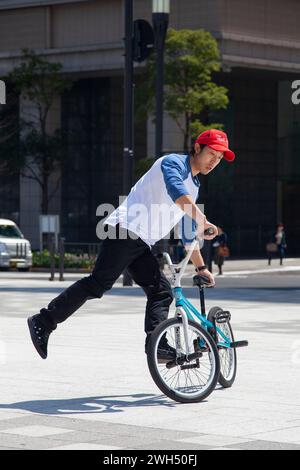 Ein japanischer BMX-Fahrer führt auf einem öffentlichen Platz mitten im Geschäftsviertel in Tokio, Japan, Tricks aus. Stockfoto