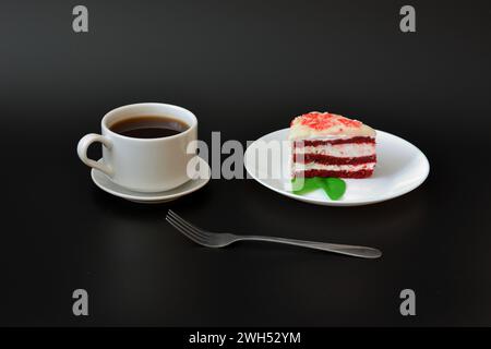 Ein Teller mit einem Stück frischer roter Samtkuchen, einer Gabel und einer Tasse heißem schwarzen Kaffee auf schwarzem Hintergrund. Nahaufnahme. Stockfoto