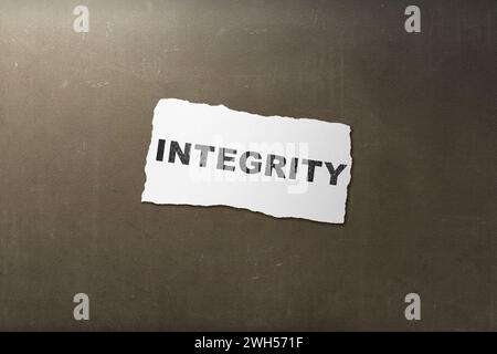Gerissenes Papier mit Integritätstext auf schwarzem Hintergrund. Reputation Integrity-Konzept Stockfoto