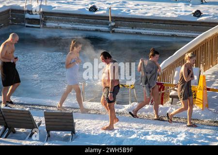 Gäste, die in der Sauna im schneebedeckten Allas Sea Pool in Helsinki, Finnland, ein- und aussteigen Stockfoto