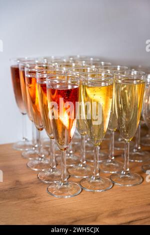 In eleganten Flöten servierte Reihen von Rosenblüten und Weißwein warten auf einen Anstoss auf eine feierliche Veranstaltung. Stockfoto