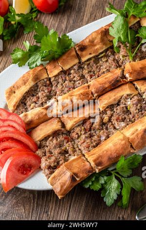 Traditionelles türkisches Hackfleisch-Pita mit Tomaten und Gemüse auf Holztisch Stockfoto