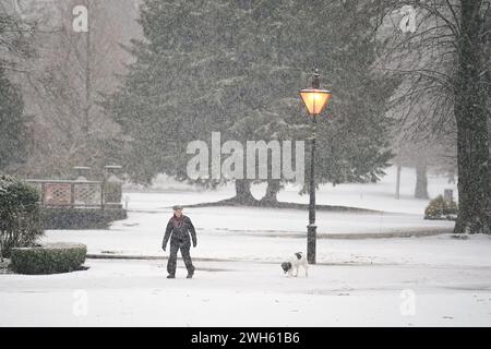Eine Person geht mit einem Hund durch Pavilion Gardens, Buxton, Peak District. In Teilen Englands und Wales werden bis zu 25 cm Schnee prognostiziert, da das Met Office Wetterwarnungen ausgab und vor Reisestörungen warnte. Bilddatum: Donnerstag, 8. Februar 2024. Stockfoto