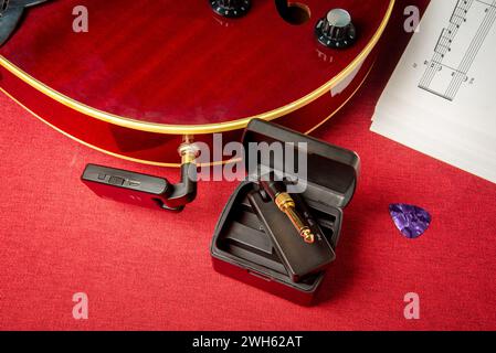 Drahtloses Gitarren-System, mit Funksender und Empfänger, mit roter hohler Jazzgitarre. Stockfoto