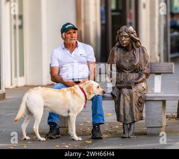 Ein Mann und sein Hund sitzen neben der Statue der Fair Magd in der Stadt Perth, Schottland Stockfoto