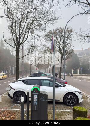 Straßburg, Frankreich - 7. Dezember 2023: Erhöhter Blick auf einen Autoladeplatz im Stadtzentrum an einem nebeligen Tag, mit einem Kia-Auto, das zwischen mehreren Autos im Hintergrund aufgeladen wird. Stockfoto
