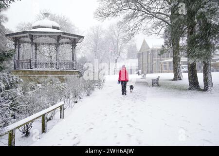 Eine Person geht mit einem Hund durch Pavilion Gardens, Buxton, Peak District. In Teilen Englands und Wales werden bis zu 25 cm Schnee prognostiziert, da das Met Office Wetterwarnungen ausgab und vor Reisestörungen warnte. Bilddatum: Donnerstag, 8. Februar 2024. Stockfoto