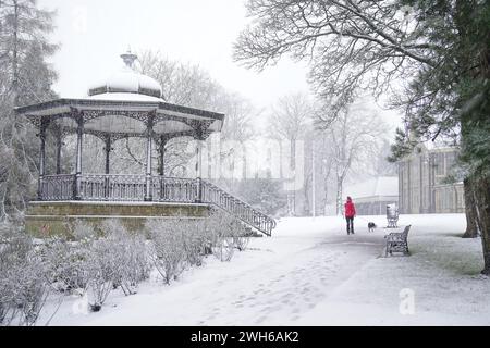 Eine Person geht mit einem Hund durch Pavilion Gardens, Buxton, Peak District. In Teilen Englands und Wales werden bis zu 25 cm Schnee prognostiziert, da das Met Office Wetterwarnungen ausgab und vor Reisestörungen warnte. Bilddatum: Donnerstag, 8. Februar 2024. Stockfoto